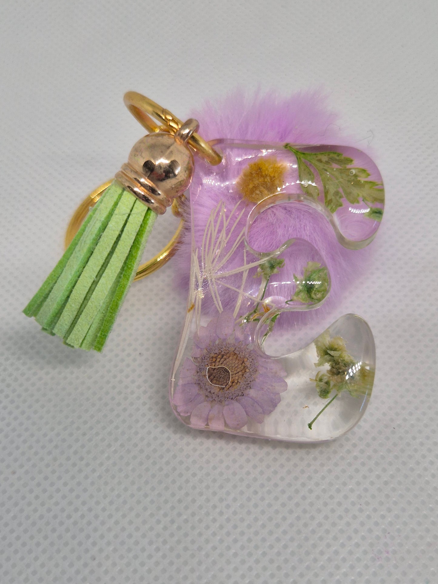 Llavero letra E transparente con flores y pompón lila