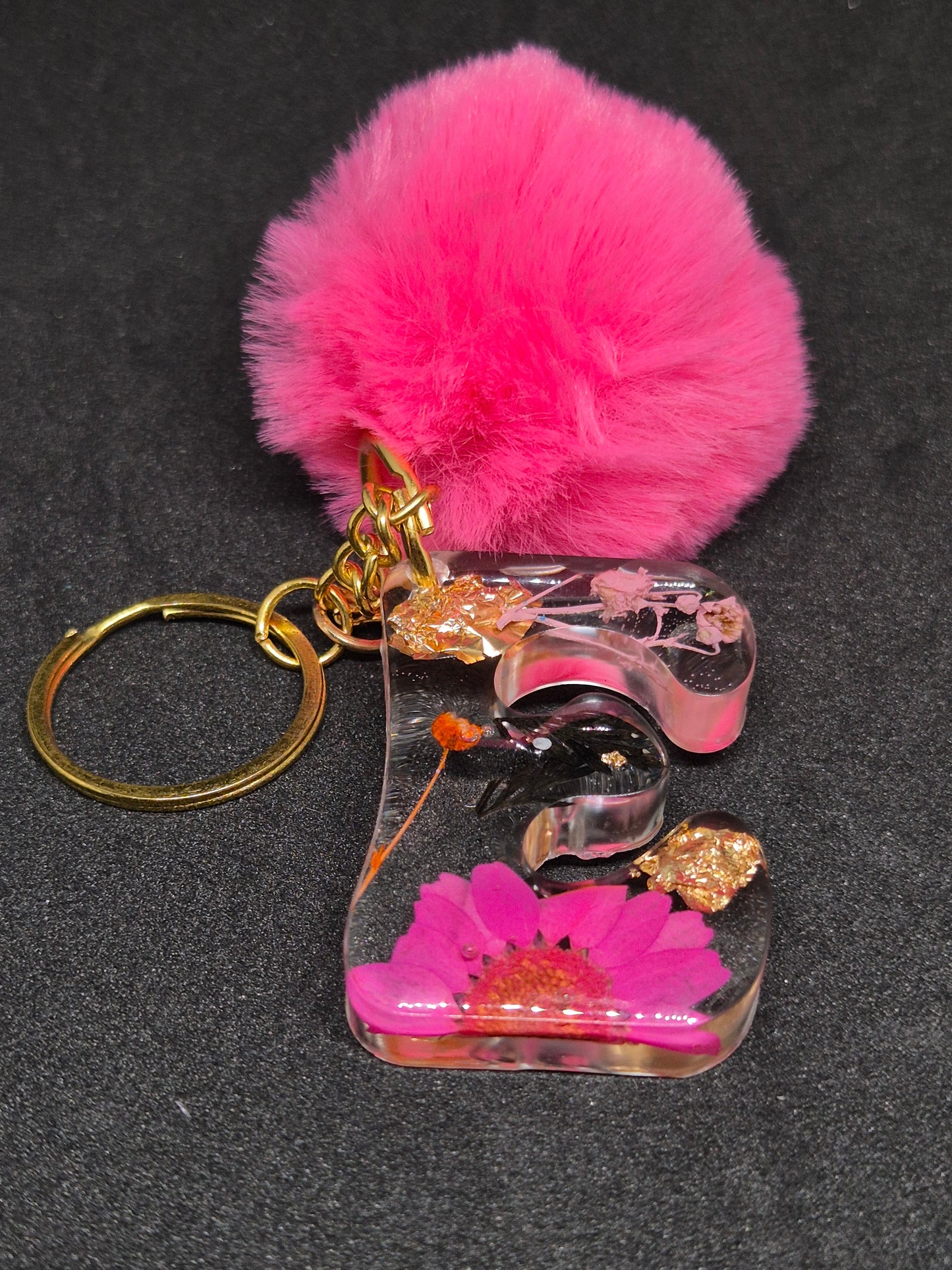 Llavero letra E transparente con flor fucsia y pompón rosa