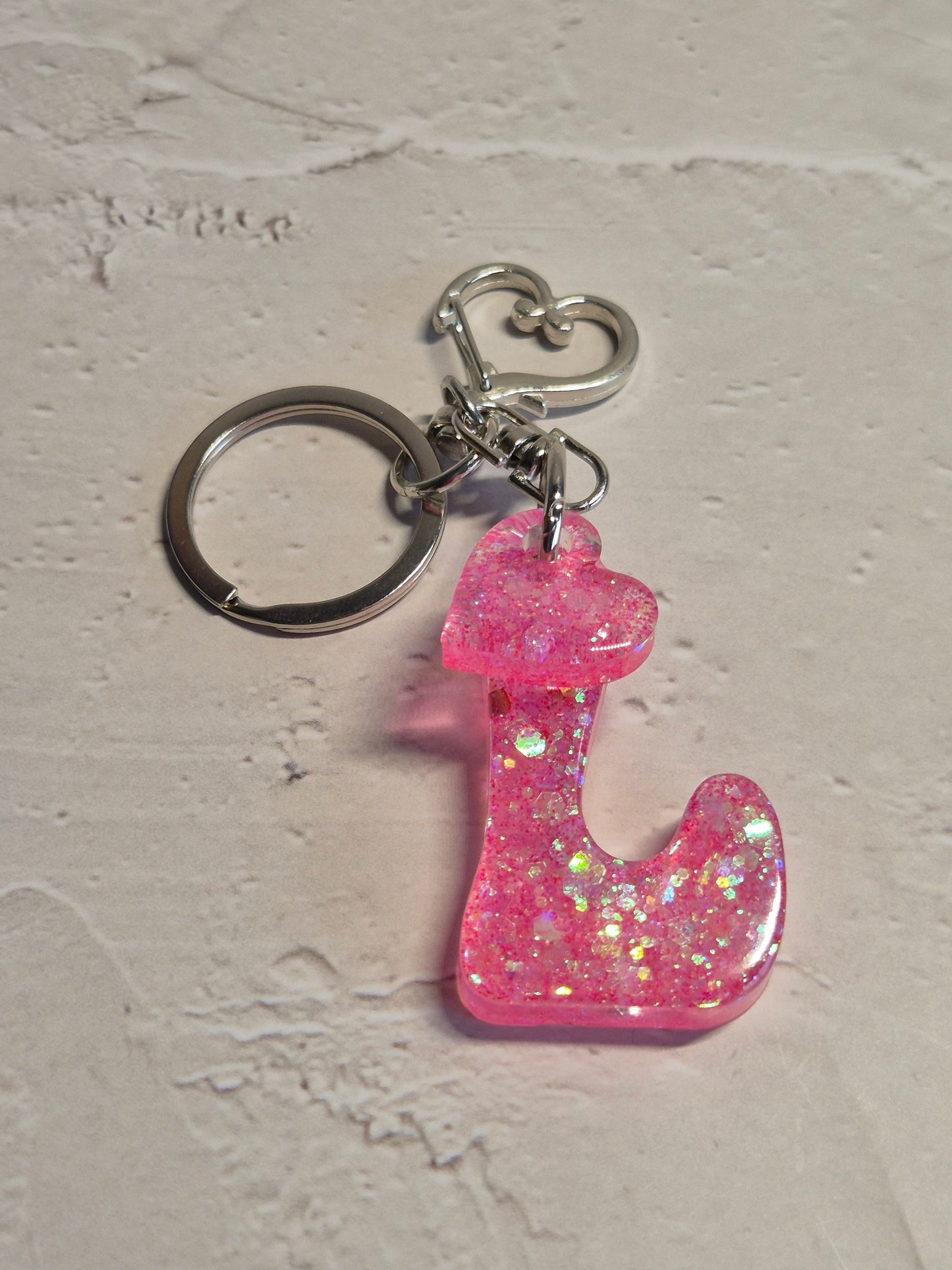 Llavero letra L de resina epoxi rosa transparente con brillo holográfico y corazón