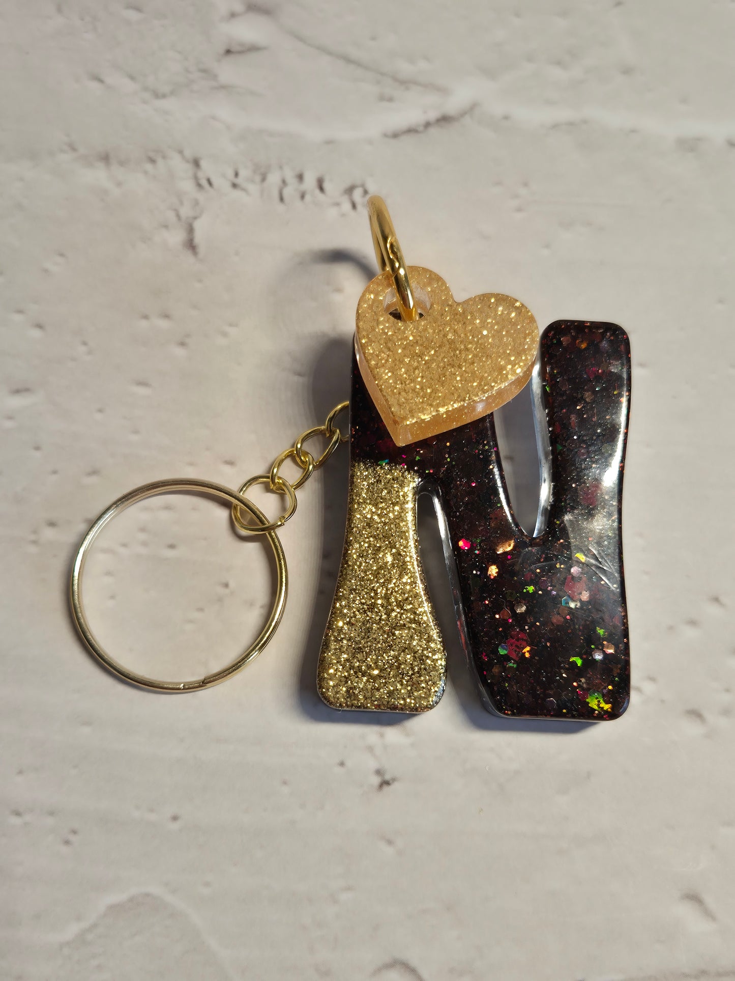 Llavero letra N de resina epoxi negro y dorado con brillo holográfico y corazón