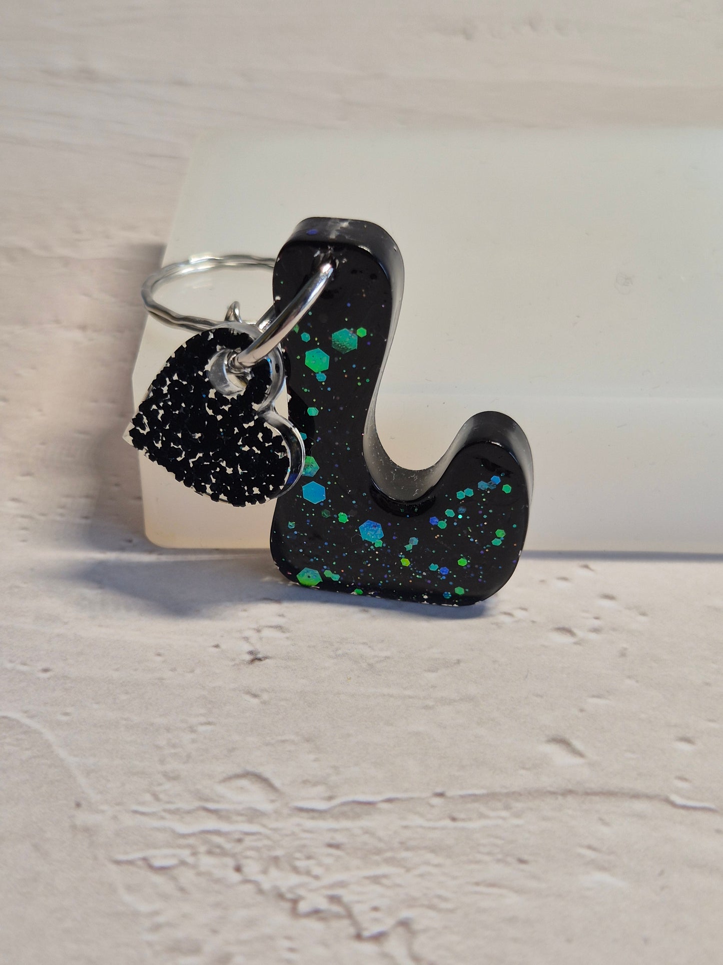 Llavero letra L de resina epoxi negra con brillo verde holográfico y corazón