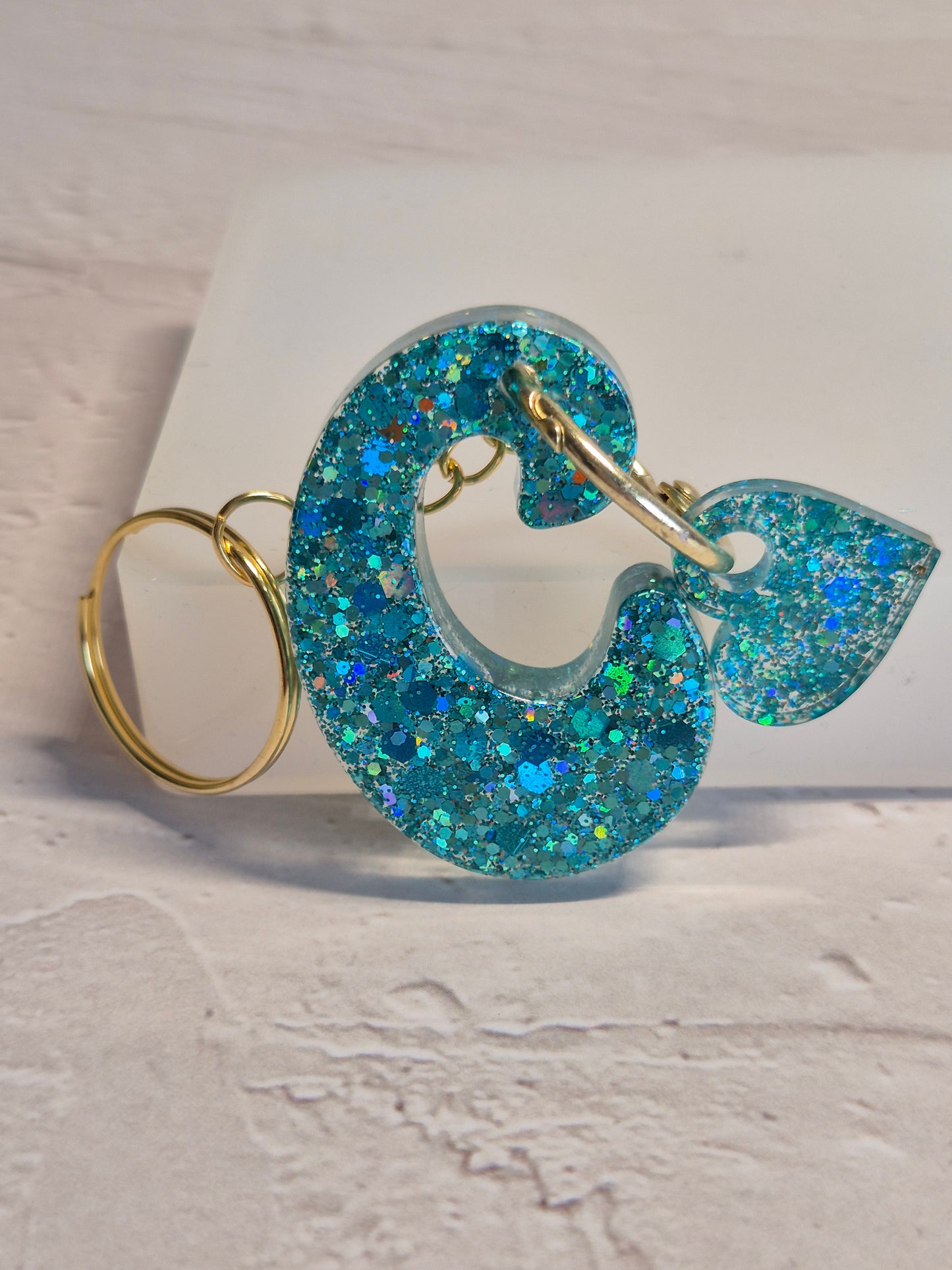 Llavero letra C de resina epoxi azul turquesa con brillo holográfico