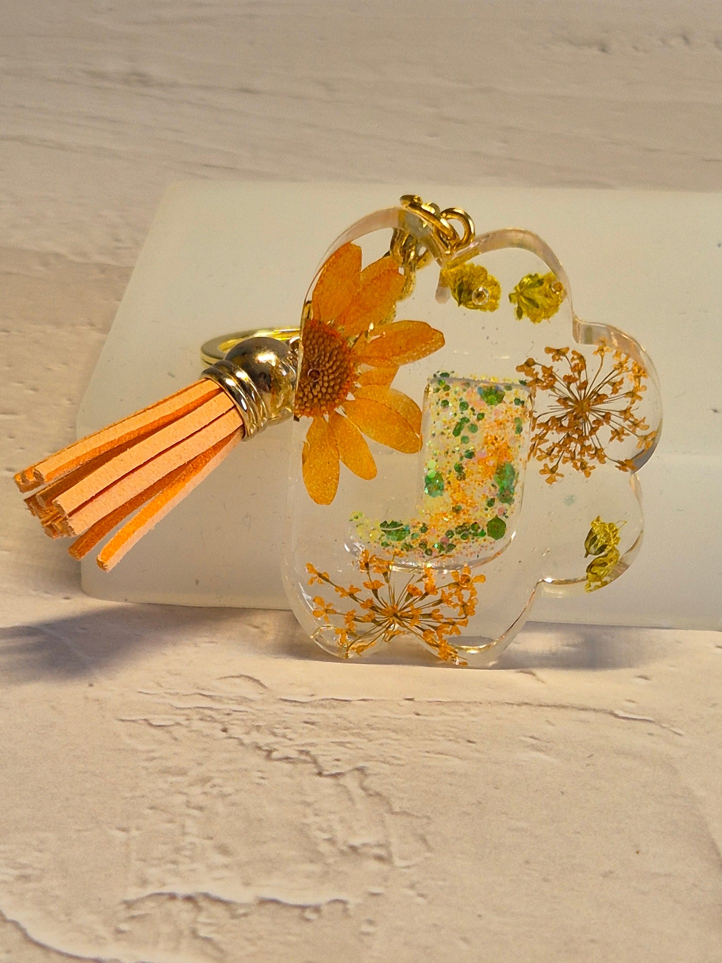 Llavero letra J de resina epoxi transparente con flores secas y borla naranja