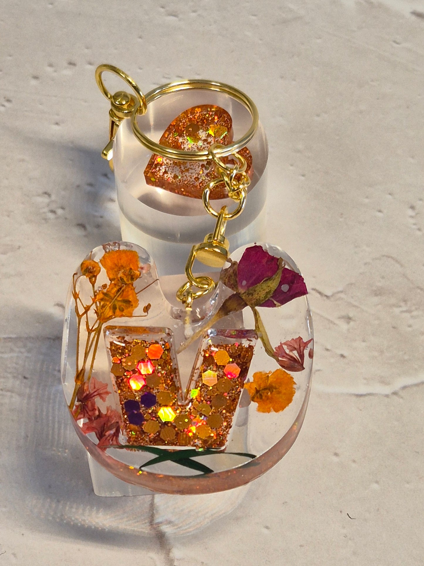 Llavero letra V de resina epoxi transparente con flores secas, glitter naranja, corazón y herrajes dorados
