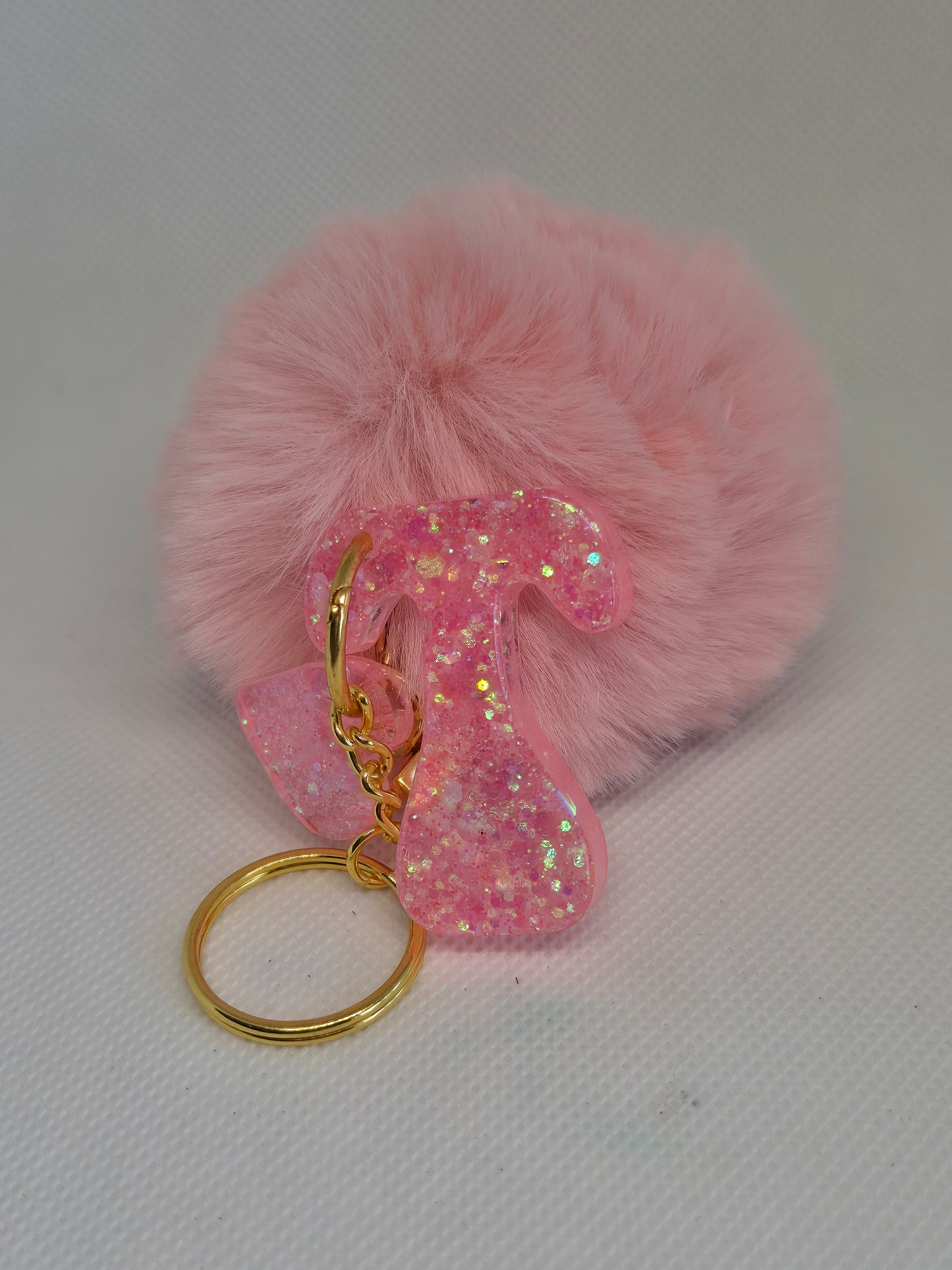 Llavero letra T en resina epoxi rosa con glitter y pompón