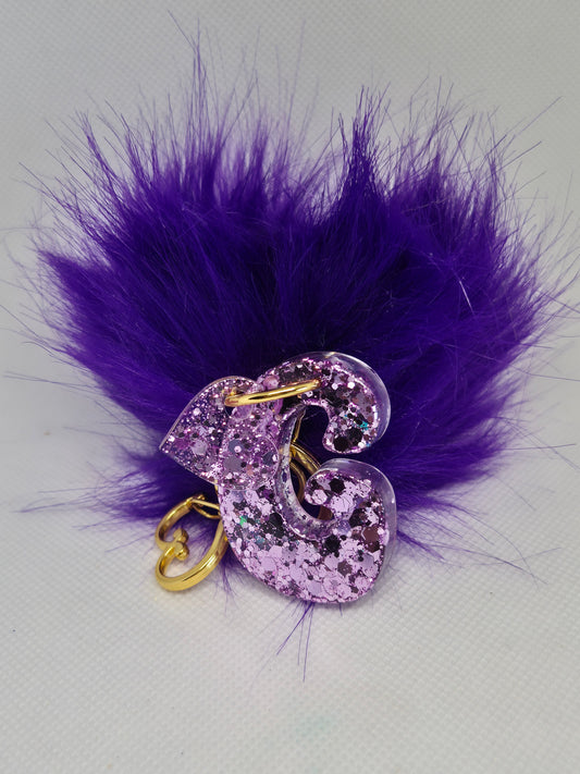 Llavero letra G en resina epoxi lila con glitter y pompón morado