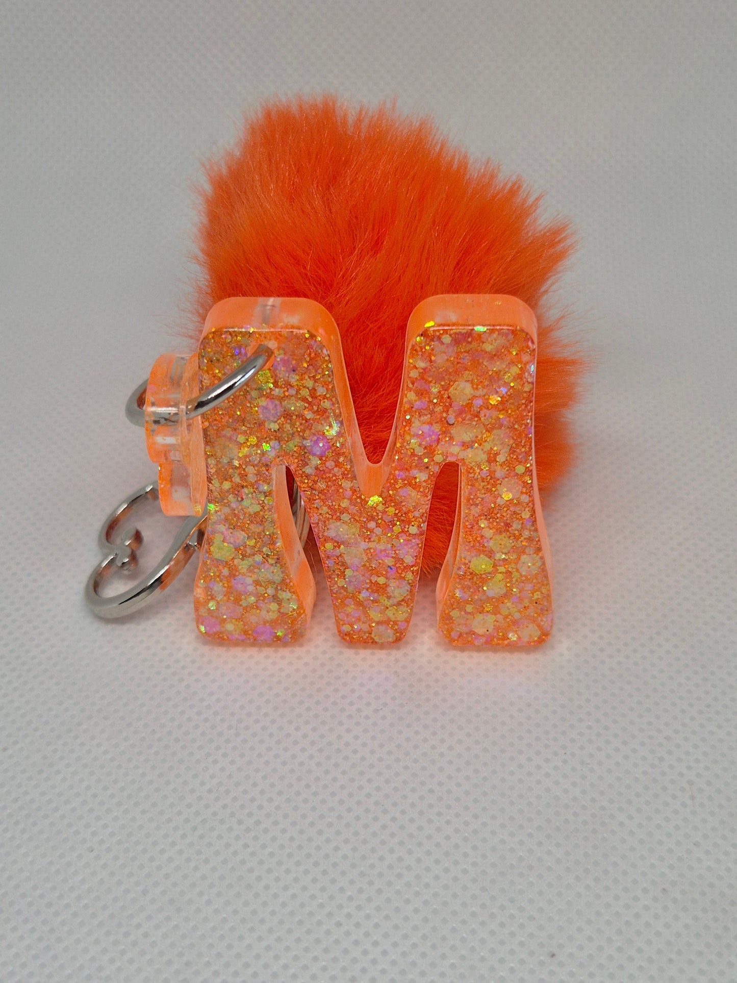 Llavero letra M naranja con pompón