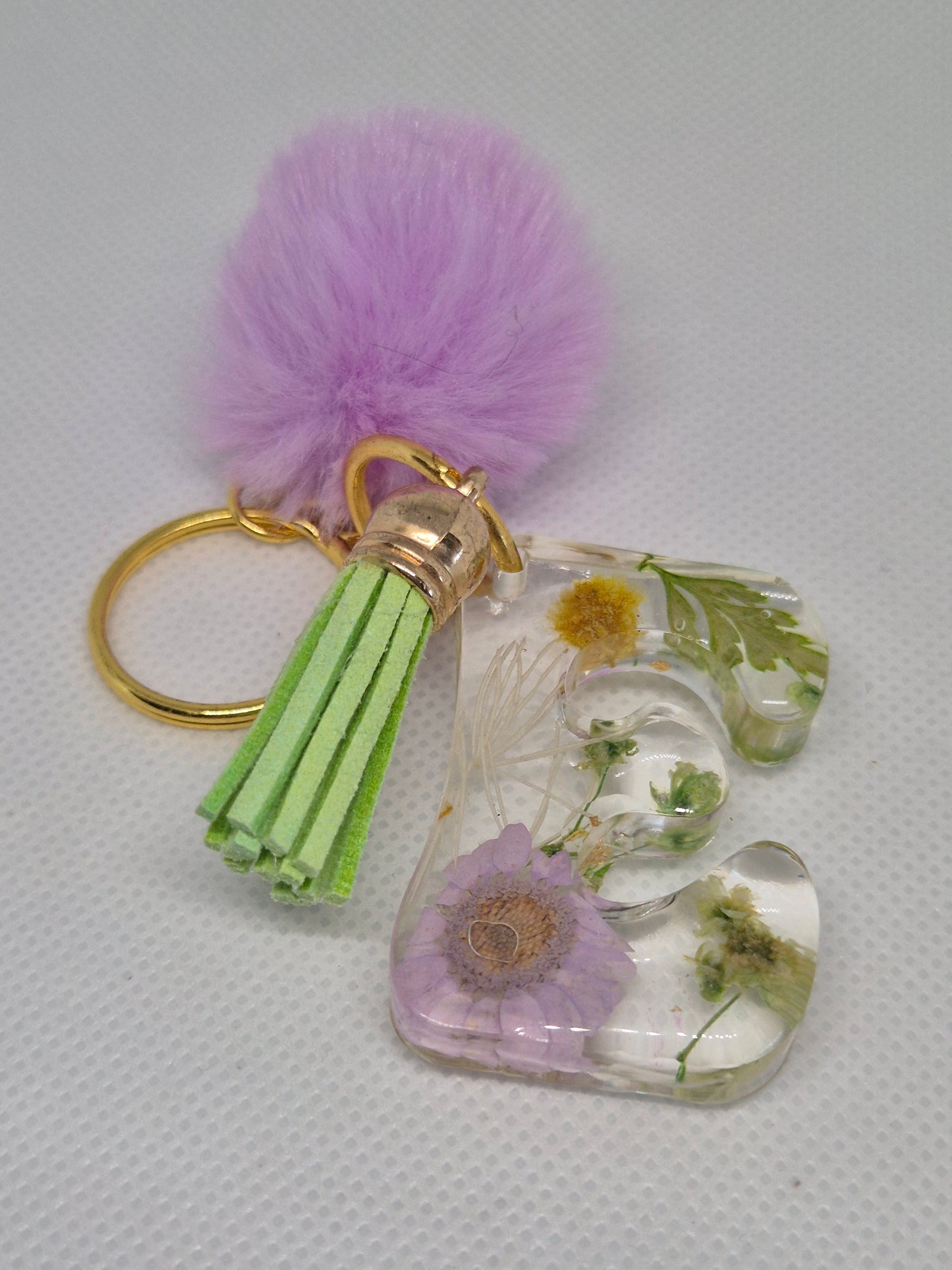Llavero letra E transparente con flores y pompón lila
