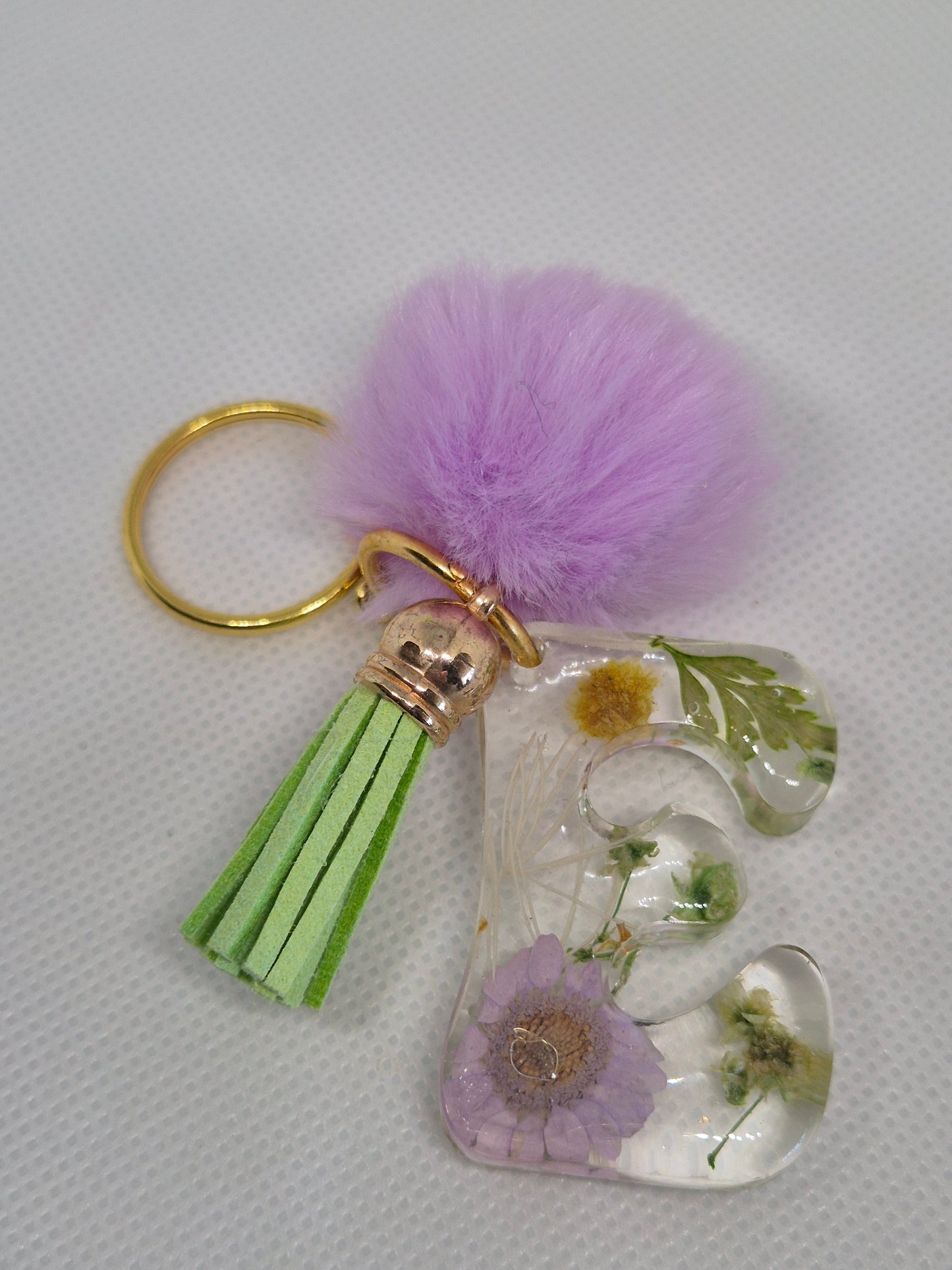Llavero letra E transparente con flores y pompón lila