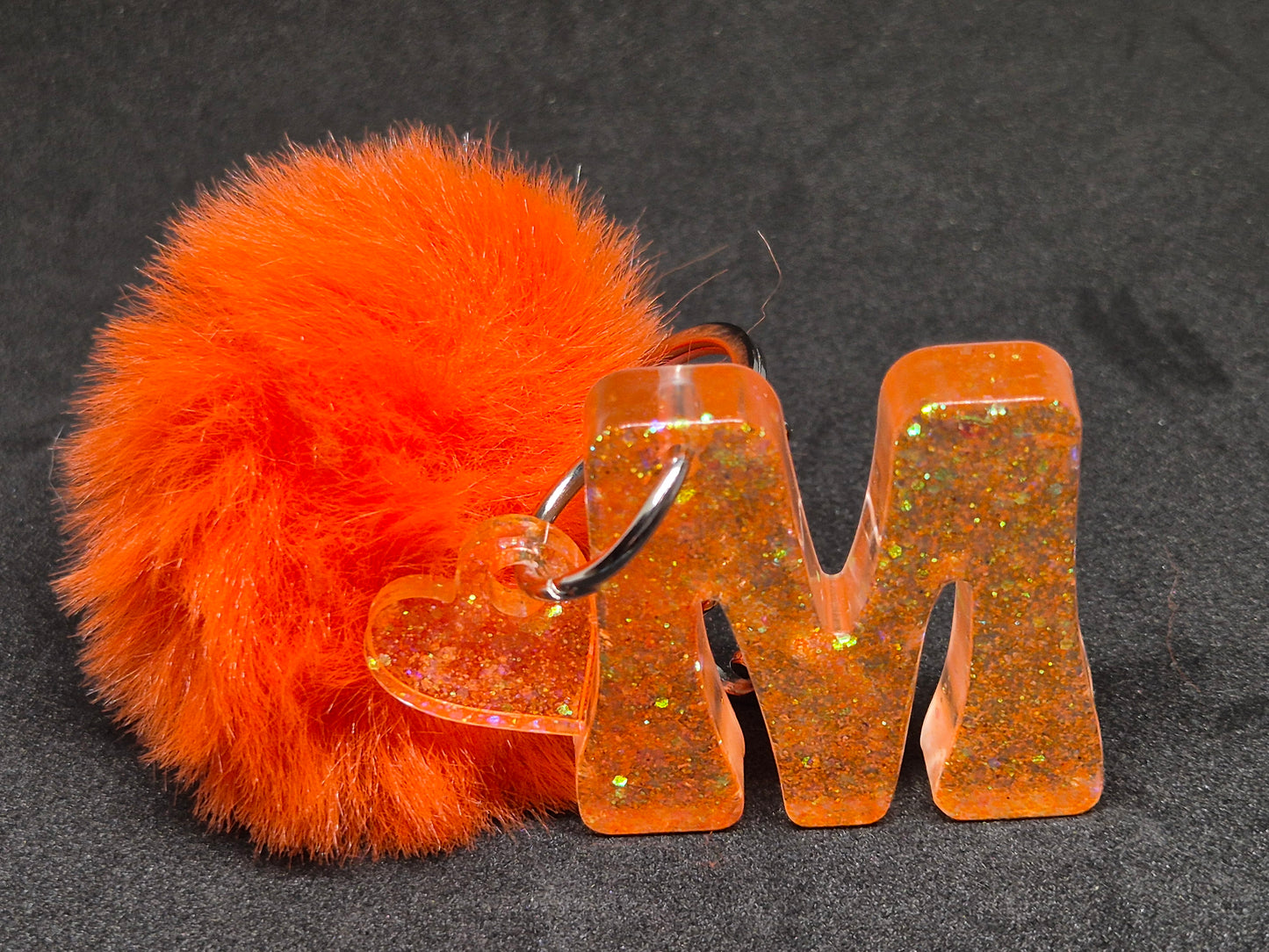Llavero letra M naranja con brillo, corazón y pompón