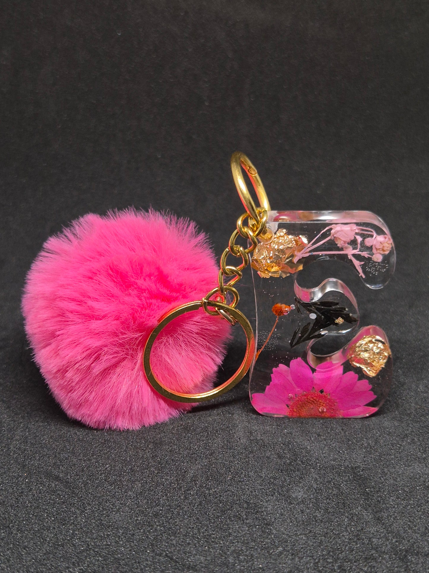 Llavero letra E transparente con flor fucsia y pompón rosa