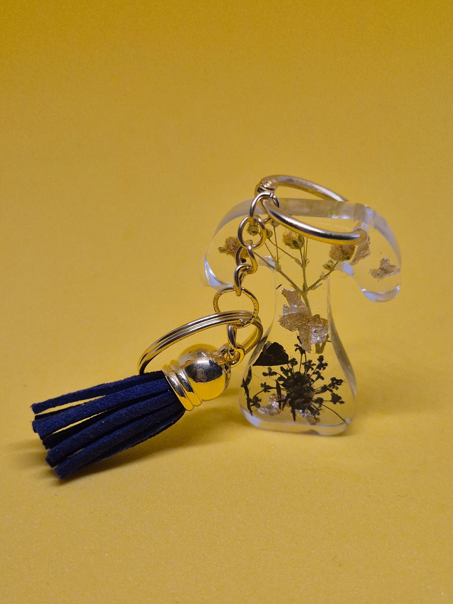 Llavero letra T de resina epoxi transparente con flores secas, pan de oro y borla azul