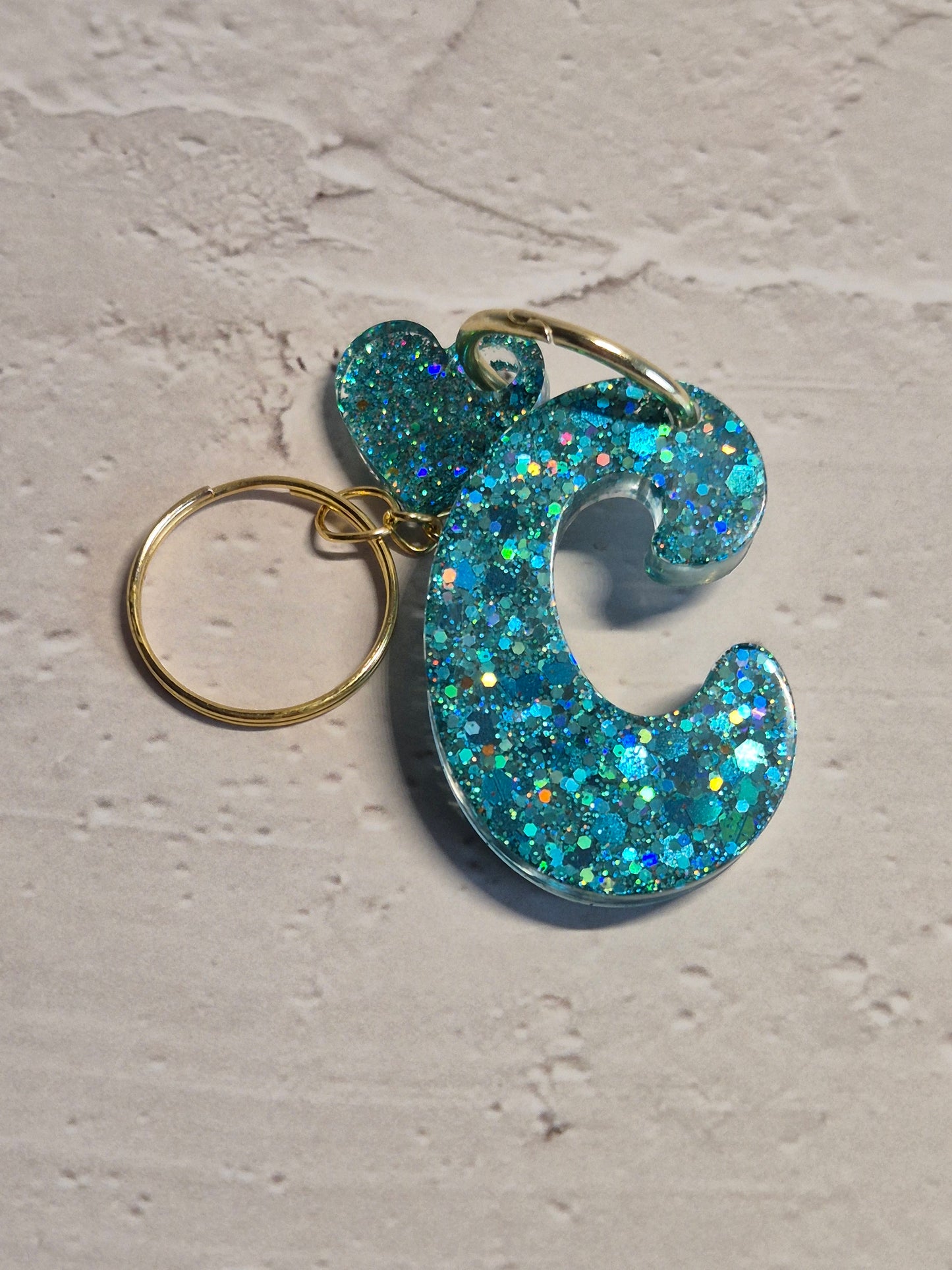 Llavero letra C de resina epoxi azul turquesa con brillo holográfico y detalle de corazón