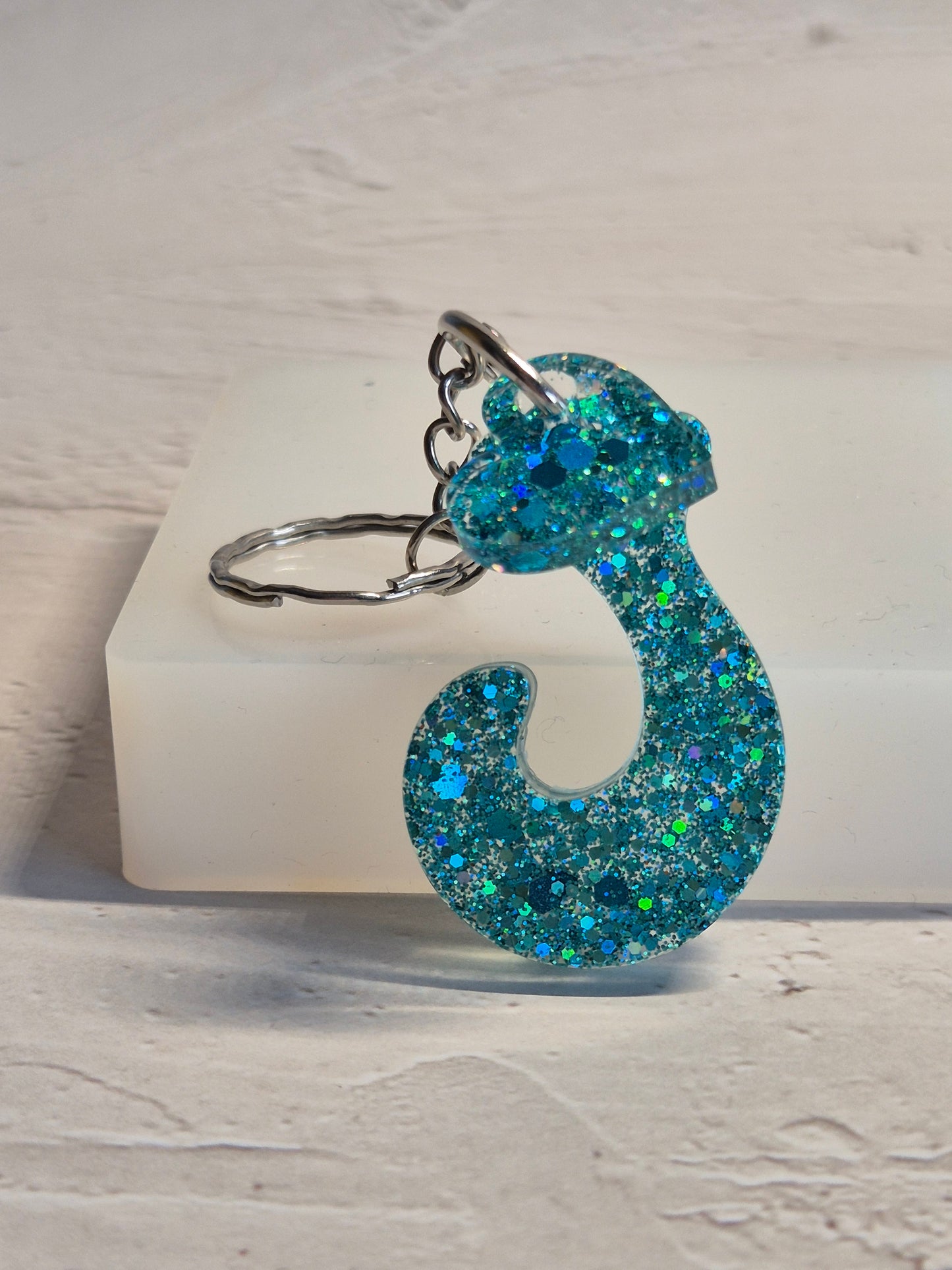 Llavero letra J de resina epoxi azul turquesa con brillo holográfico y detalle de corazón