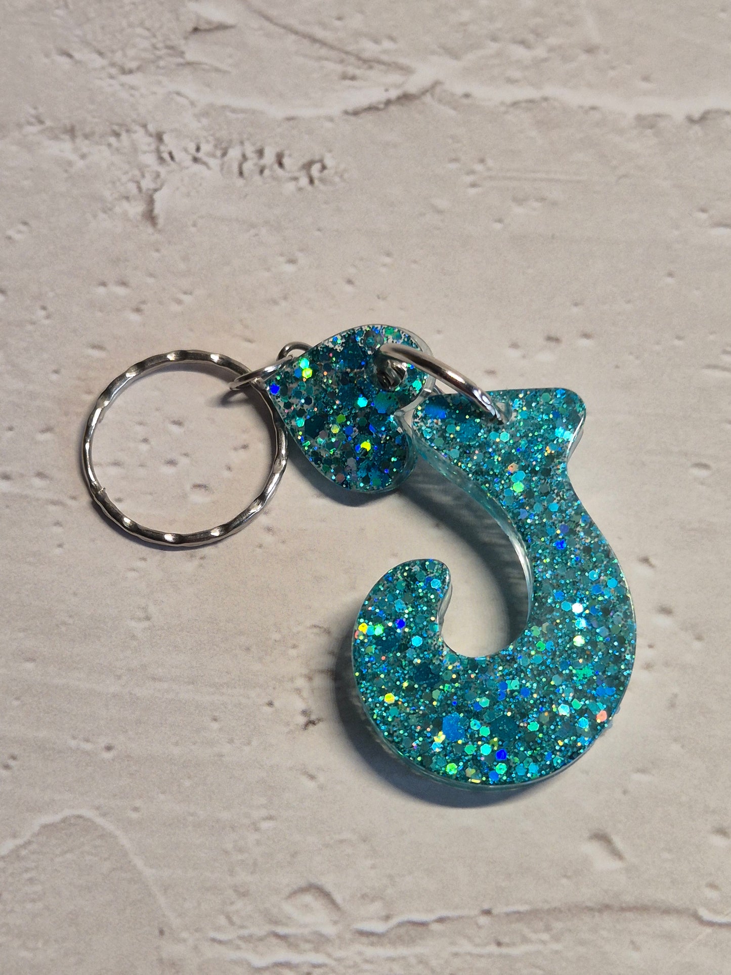 Llavero letra J de resina epoxi azul turquesa con brillo holográfico y detalle de corazón