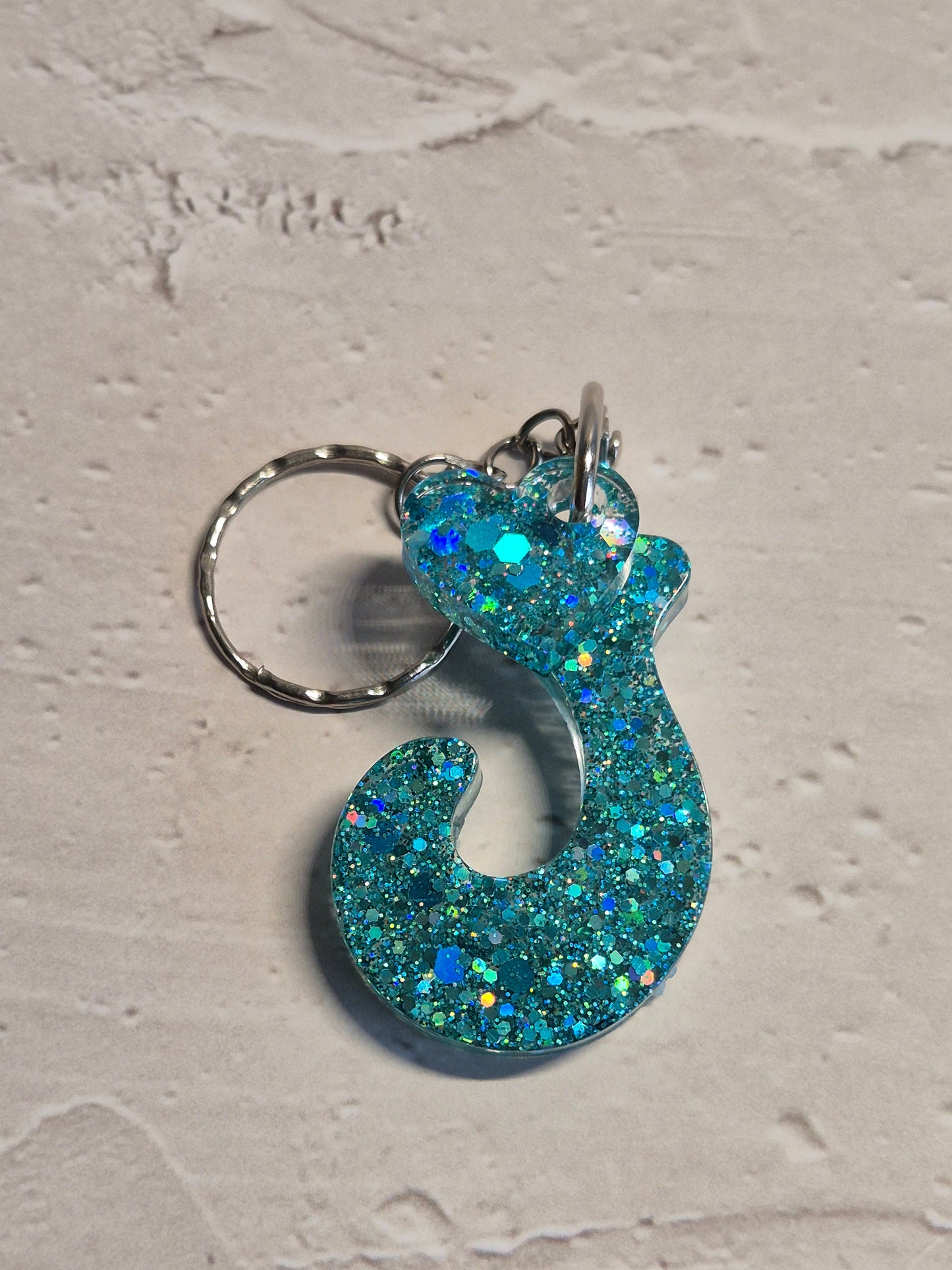 Llavero letra J de resina epoxi azul turquesa con brillo holográfico y detalle de corazón