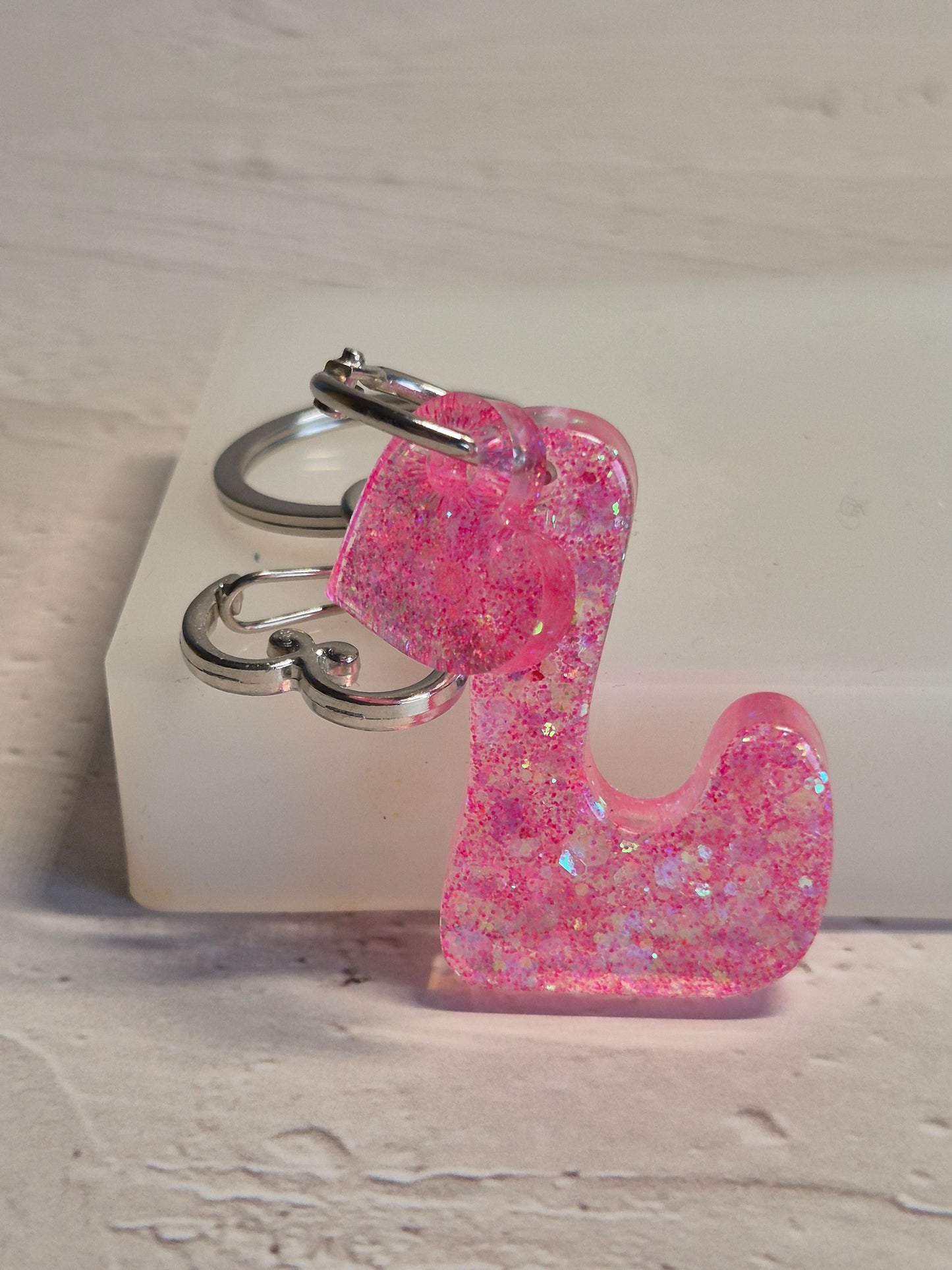 Llavero letra L de resina epoxi rosa transparente con brillo holográfico y corazón