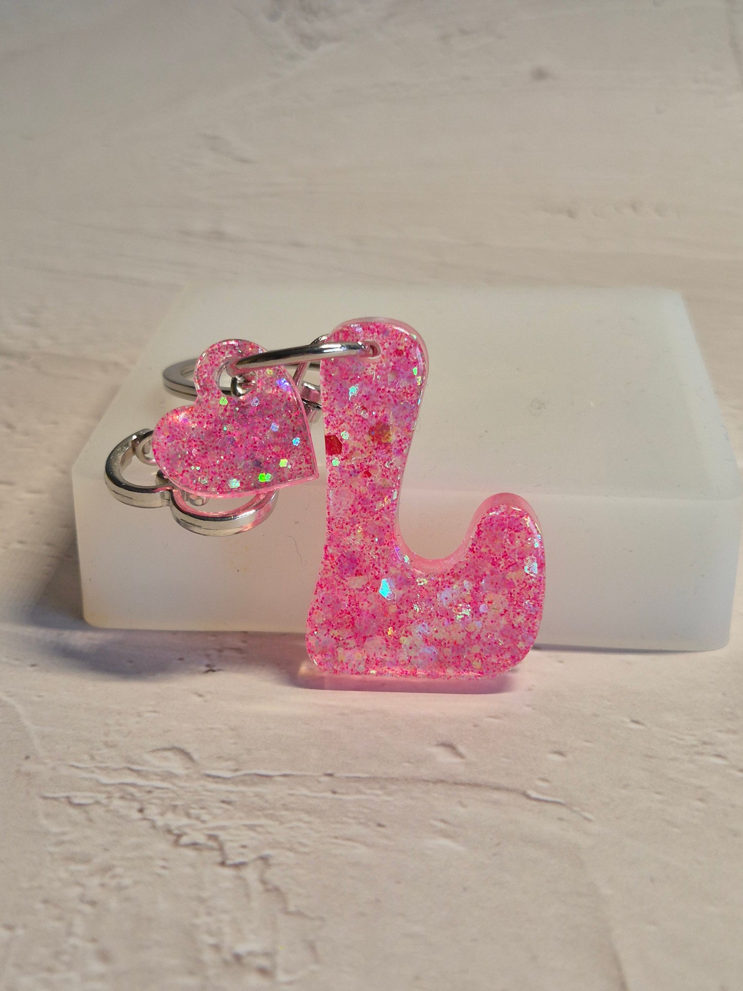 Llavero letra L de resina epoxi rosa transparente con brillo holográfico y corazón