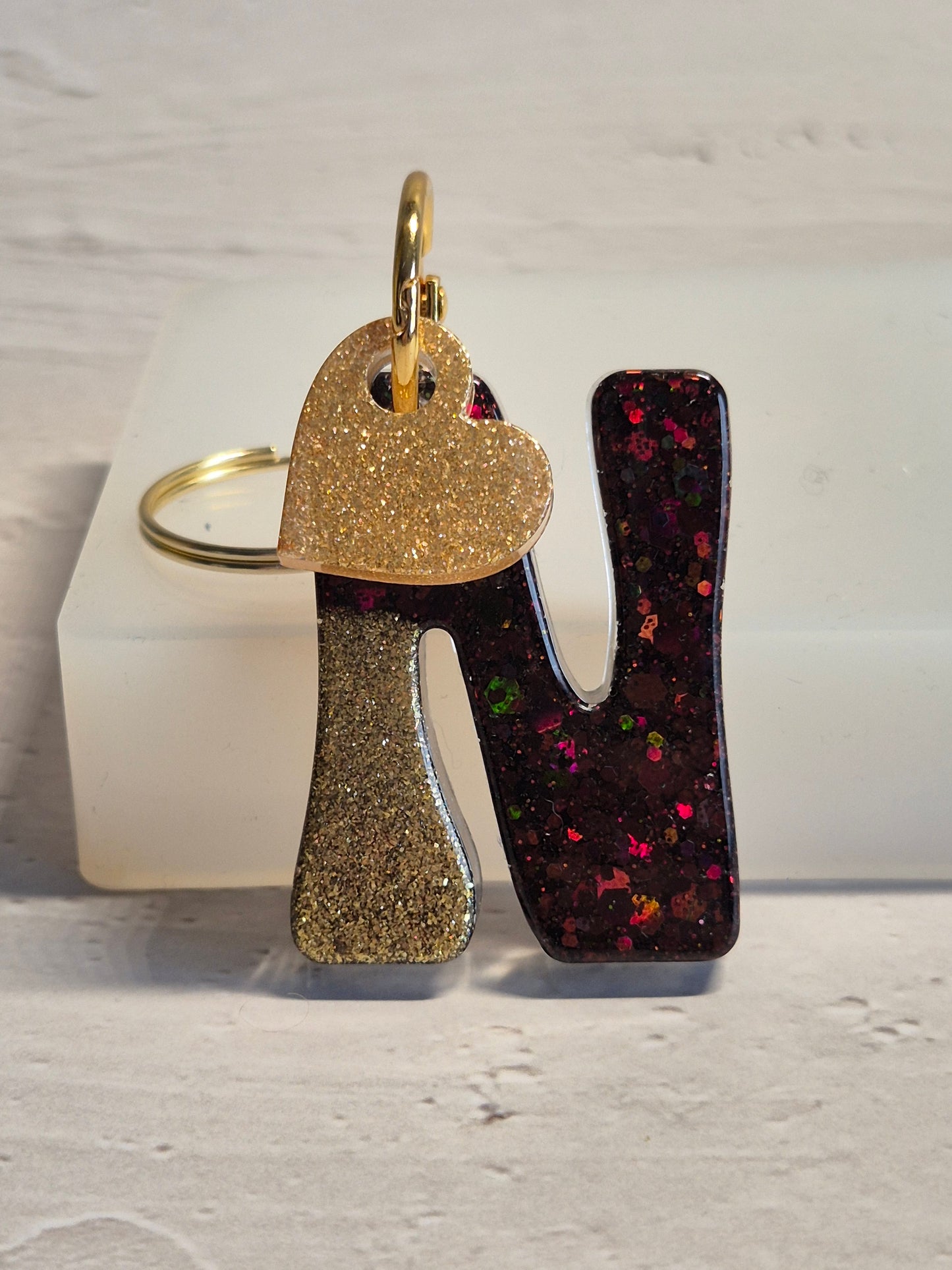 Llavero letra N de resina epoxi negro y dorado con brillo holográfico y corazón