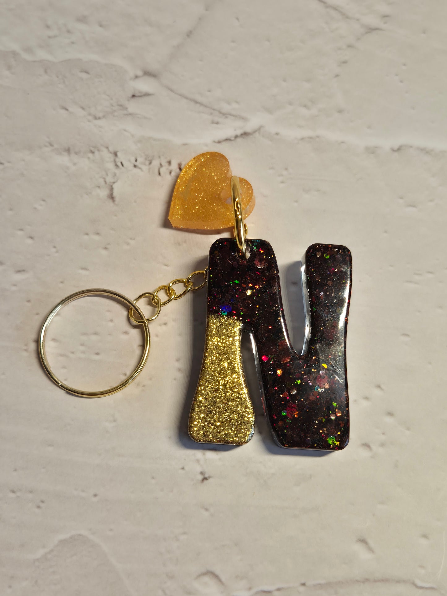 Llavero letra N de resina epoxi negro y dorado con brillo holográfico y corazón