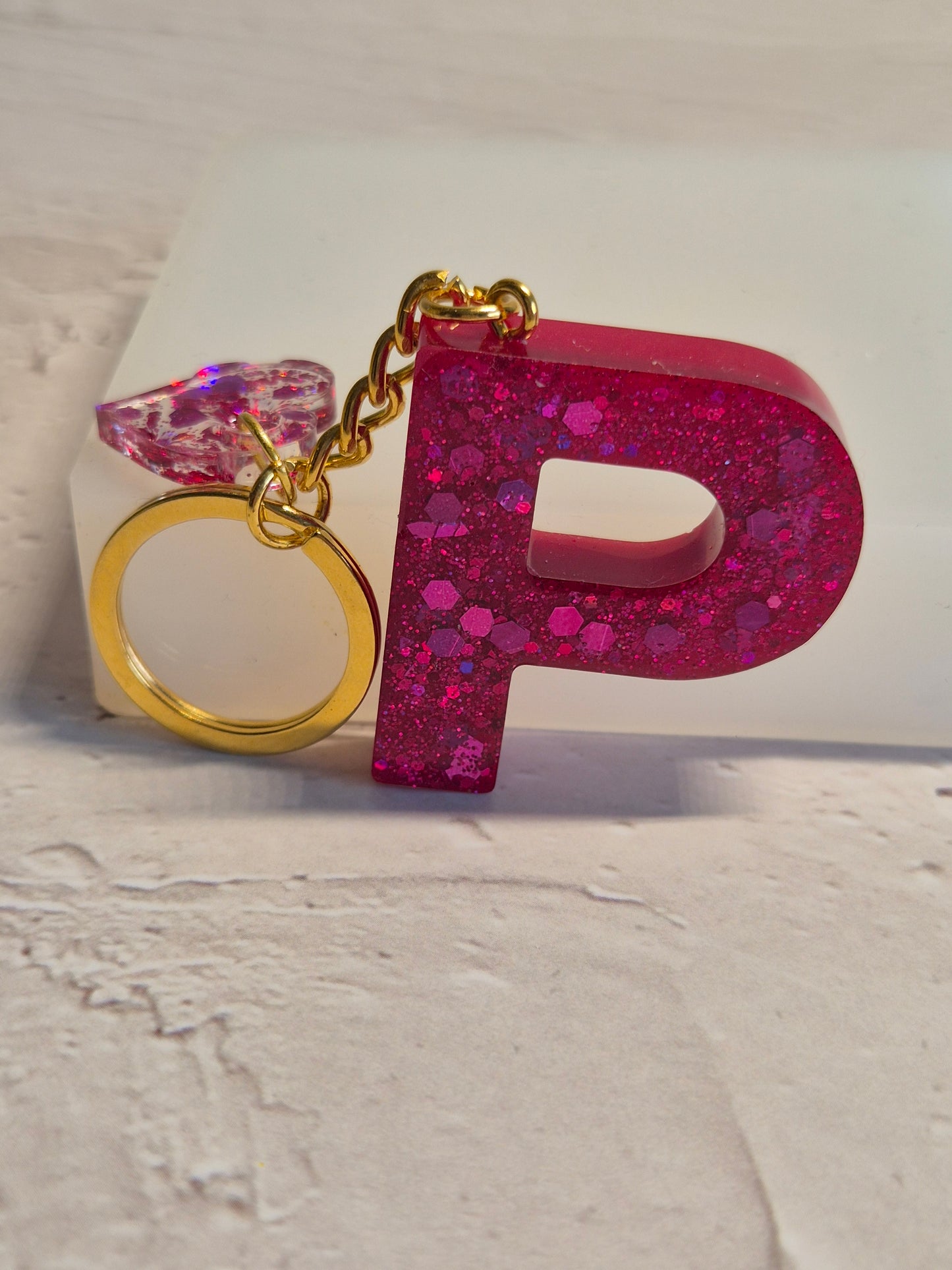 Llavero letra P de resina epoxi fucsia con brillo holográfico y corazón