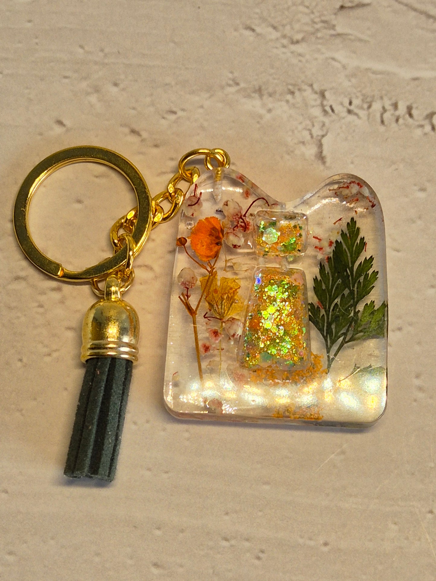 Llavero letra I de resina epoxi transparente con flores secas, hoja verde y borla verde oscuro