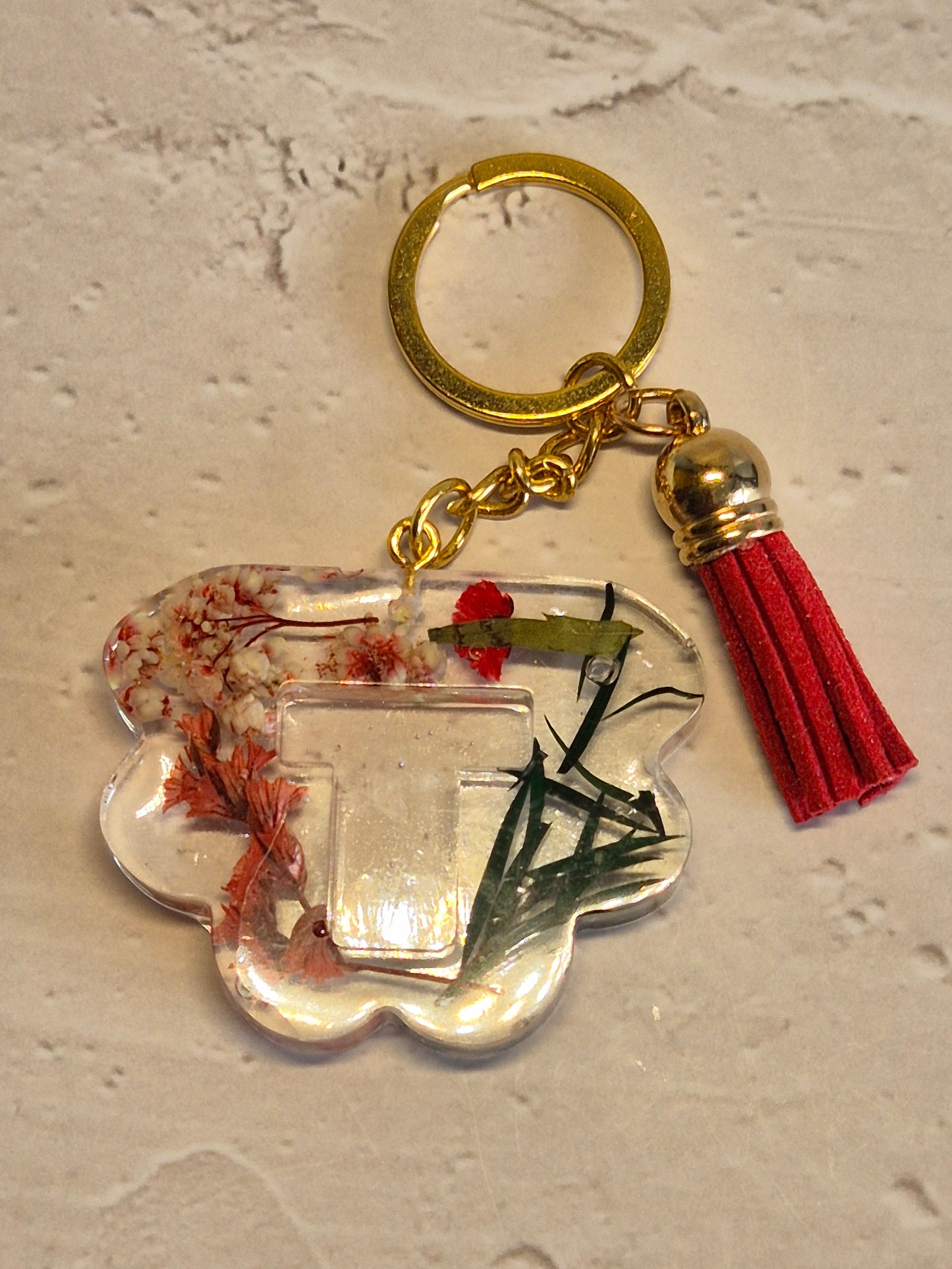 Llavero letra T de resina epoxi transparente con flores secas, hojas verdes y borla roja