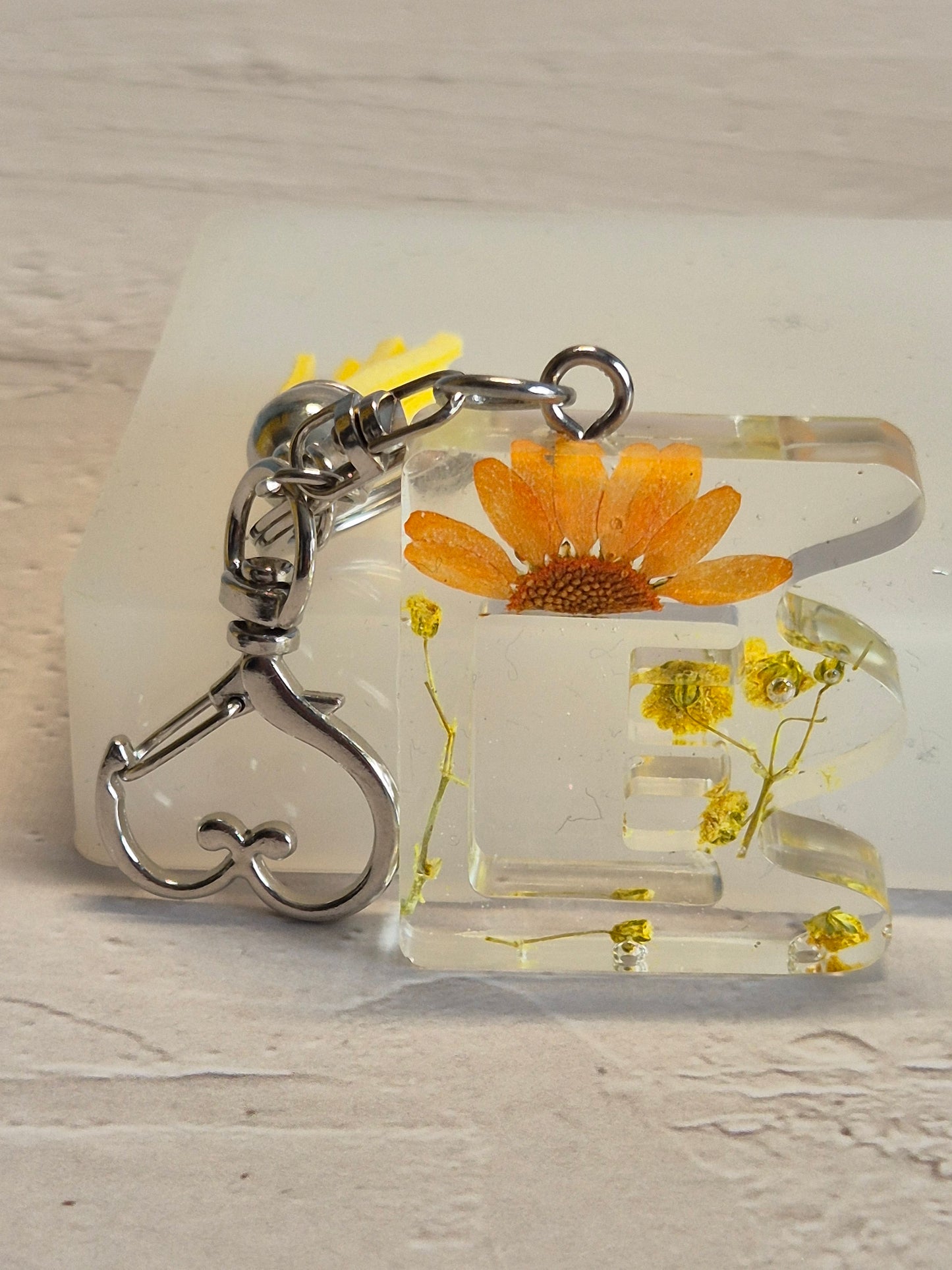 Llavero letra E de resina epoxi transparente con flores secas y borla amarilla