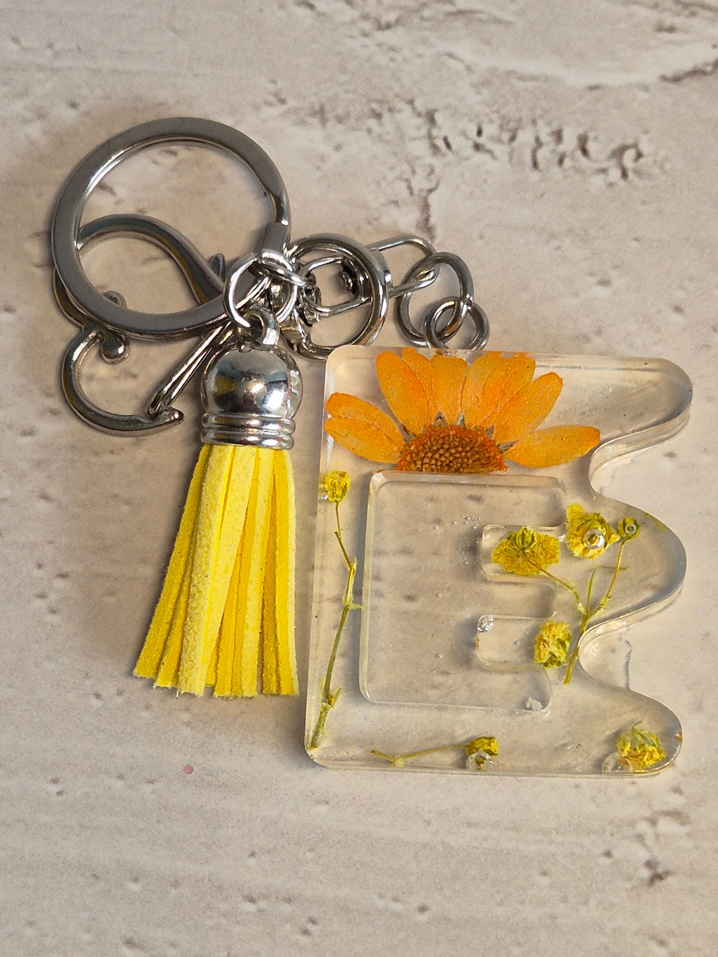 Llavero letra E de resina epoxi transparente con flores secas y borla amarilla