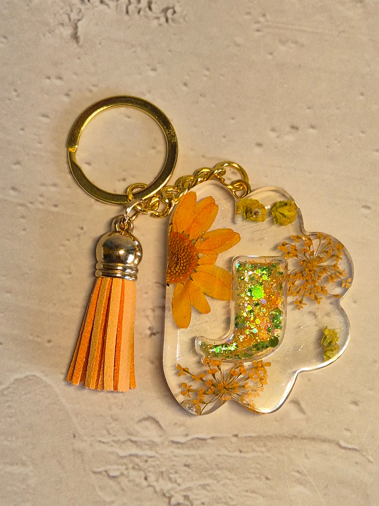 Llavero letra J de resina epoxi transparente con flores secas y borla naranja
