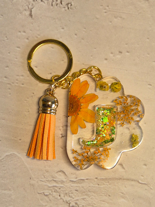 Llavero letra J de resina epoxi transparente con flores secas y borla naranja