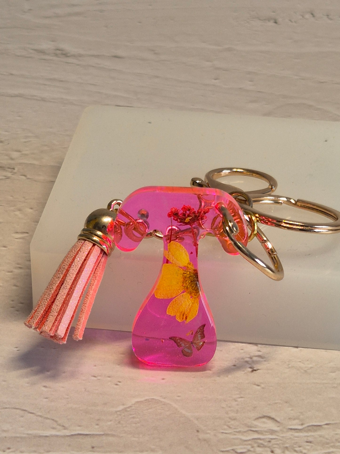 Llavero letra T de resina epoxi rosa transparente con flores secas y borla rosa