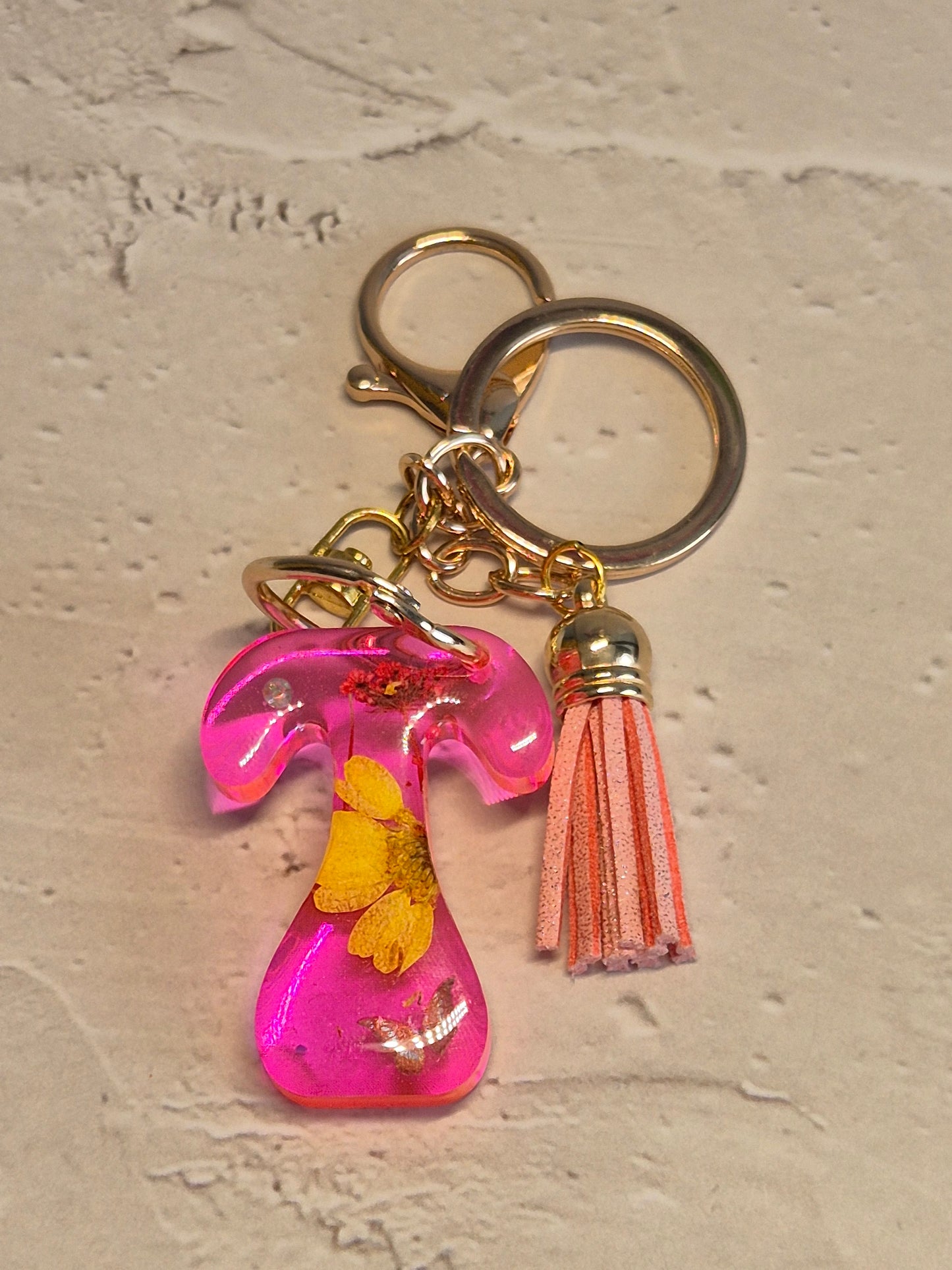 Llavero letra T de resina epoxi rosa transparente con flores secas y borla rosa