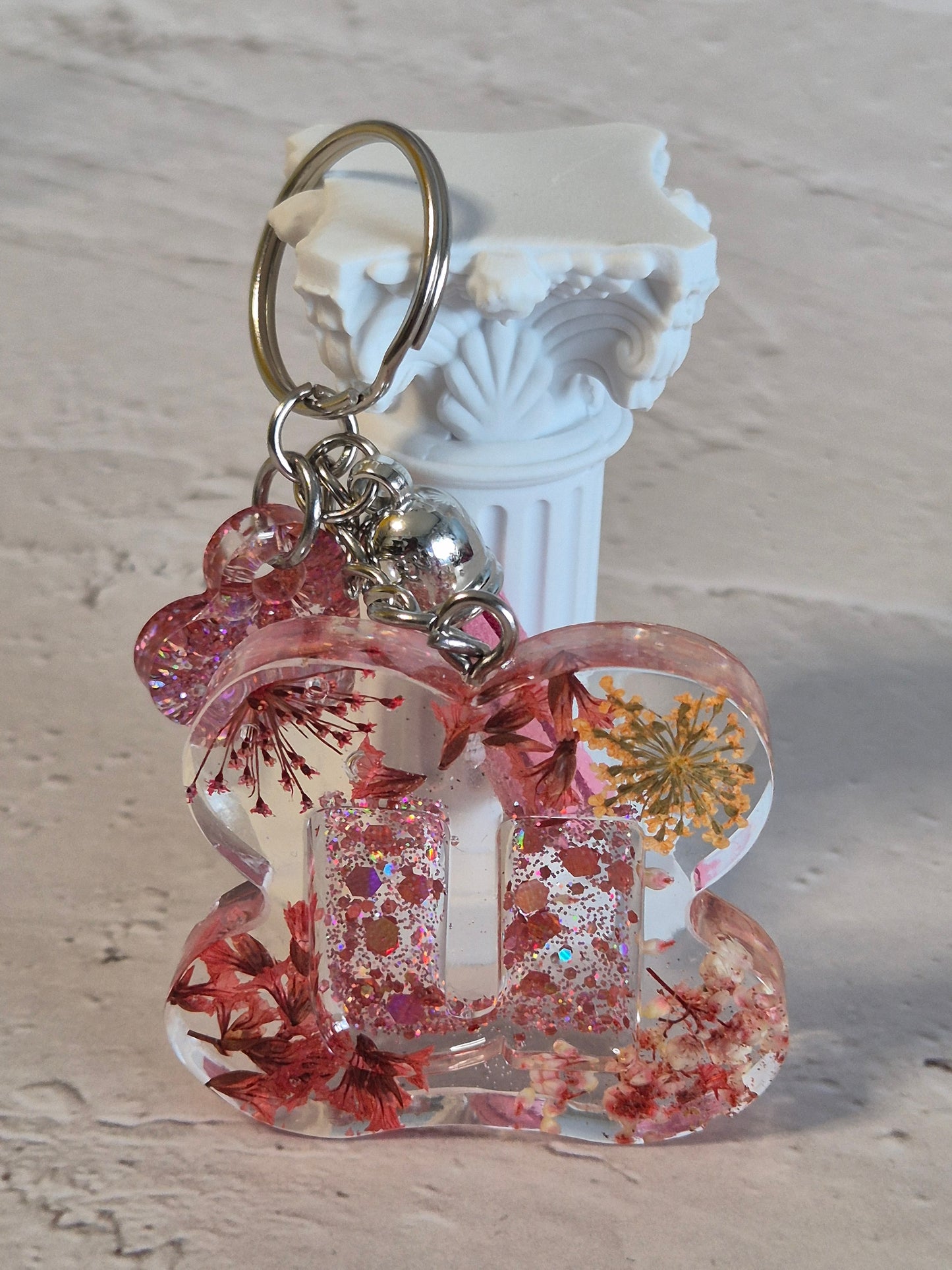 Llavero letra U de resina epoxi transparente con flores secas, glitter y borla rosa